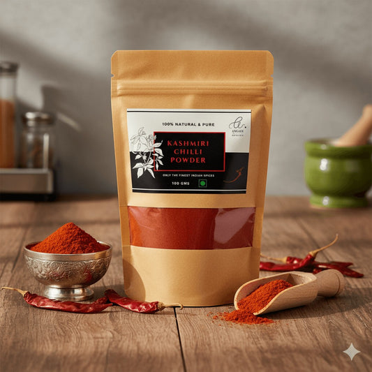 Angadi of Spices Kashmiri Chilli Powder in a resealable pouch, with a small bowl and wooden scoop of powder, and dried chillies.