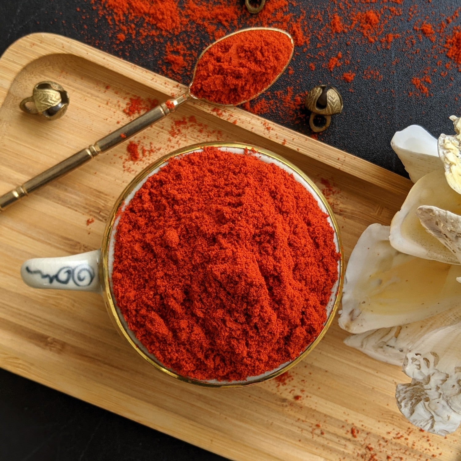 Angadi of Spices Kashmiri chilli powder in a decorative bowl and spoon, vibrant red hue, minimum pungency, rich in vitamins and iron.