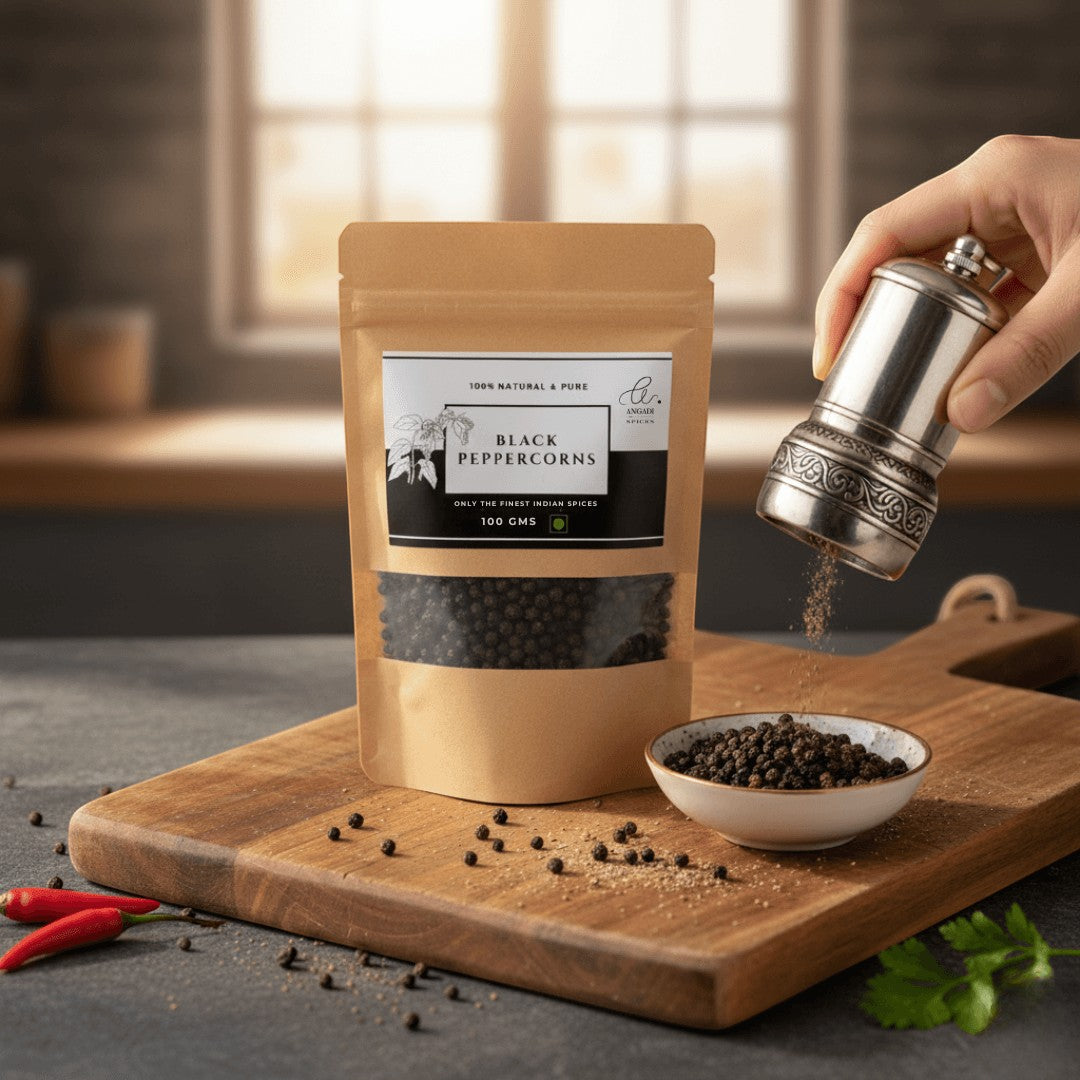 Angadi of Spices whole black peppercorns, TGSEB grade, 100gms in a resealable pouch. Freshly ground pepper is being dispensed from a silver mill.